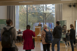 Viele Studierende schauen Richtung Pult, an dem eine Frau spricht.