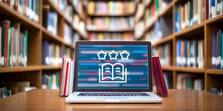 Photo: A laptop is sitting on a table in a library, with a book icon displayed on its screen.