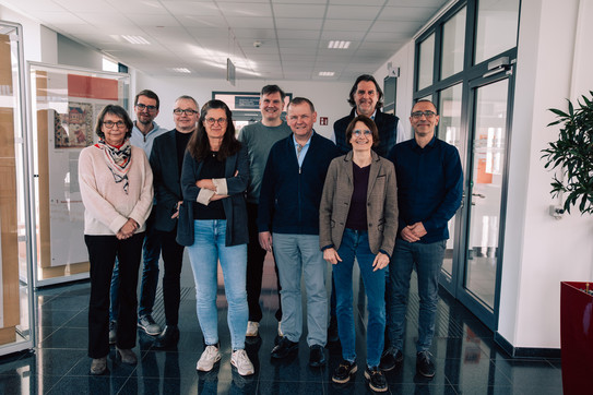 Foto: Neun Personen stehen in einem Flur und lächeln in die Kamera