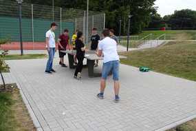 do-camp-ing Teilnehmerinnen und Teilnehmer spielen zusammen Tischtennis.