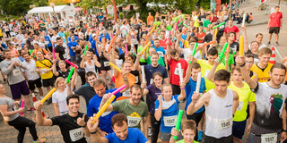 Staffelläufer beim Campuslauf Läuferinnen und Läufer halten ihre Staffelstäbe hoch.