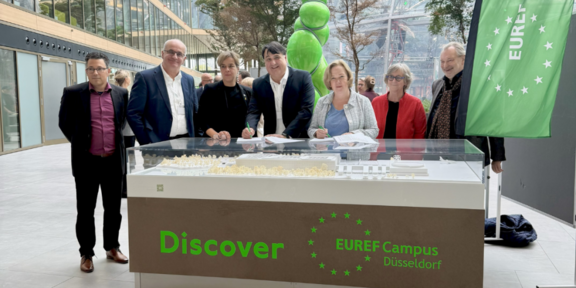 Gruppenfoto auf dem Talent-Campus Düsseldorf vor einem modernen Seminar- und Veranstaltungsbereich.