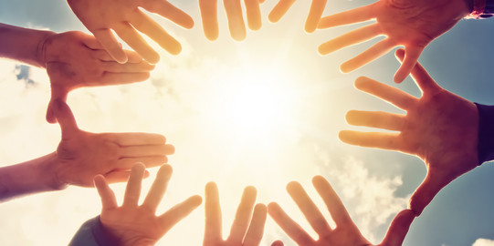 Zehn Hände bilden einen Kreis um eine Sonne