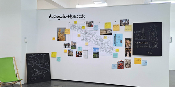 Route Mittelalter Ruhr_Ausstellung Eine Karte, Fotos und bunte Zettel mit Informationen hängen an einer Wand