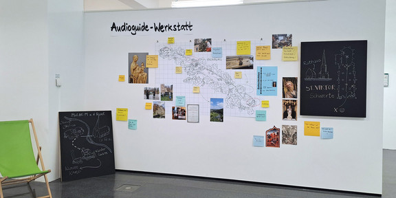 A map, photos and colorful pieces of paper with information hang on a wall