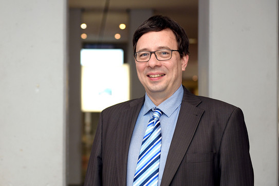 Porträtfoto von Prof. Jörg Rahnenführer: Ein Mann mit dunklen Haaren und Brille lächelt in die Kamera.