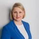 Porträtfoto von Gudrun Engel. Gudrun Engel steht in einem blauen Blazer vor einer weißen Wand.