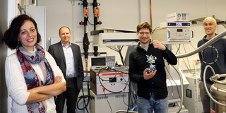 One woman and three men standing in a laboratory