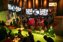Photo: View into an event hall with guests standing at tables.