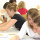 Studierende im Seminarraum sitzen in Partnerarbeit an ein paar Textstreifen.