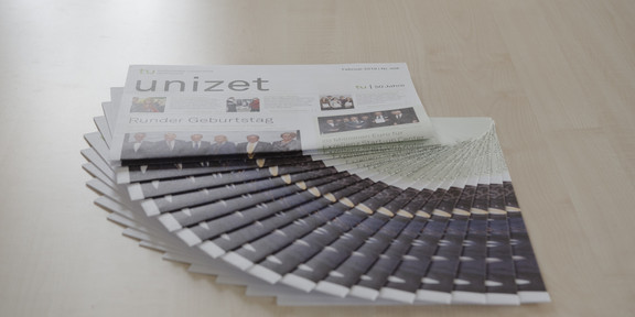 Several issues of unizet lie fanned out on a table