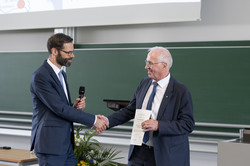 Two men in suits shake hands.