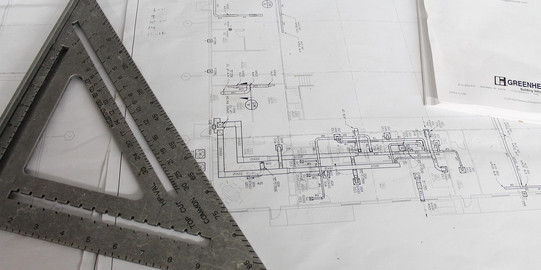 Auf einem Papier mit Handzeichnung zum Thema Architektur liegt ein silbernes Geodreieck