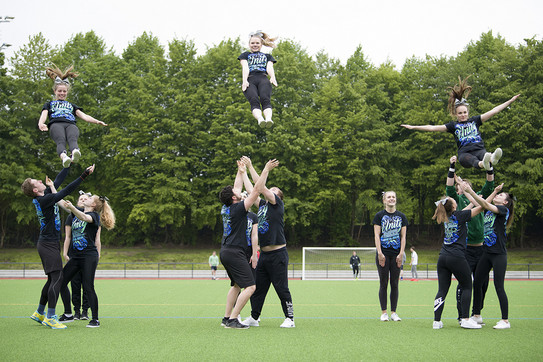 Die Cheerleader der TU Dortmund bieten eine Formation auf den Außensportanlagen dar.
