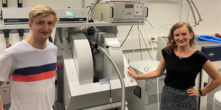 Electron Paramagnetic Resonance Spectroscopy A man and a woman stand next to an electron paramagnetic resonance spectrometer in a laboratory.