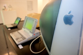 Im Vordergrund ein älterer Mac Bildschirm, im Hintergrund zwei alte Laptops
