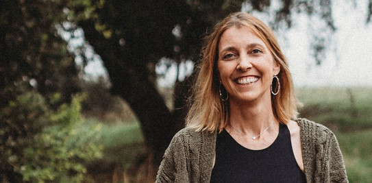 Porträtfoto von Prof. Julia K. Vogel: Ein körniges Bild, das Prof. Julia K. Vogel in der Natur zeigt. Sie hat blonde Haare. Im Hintergrund steht ein Baum auf einer Wiese.