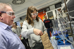 Eine Schülerin wiegt im Labor ein Pulver ab, ein Mann schaut ihr dabei zu