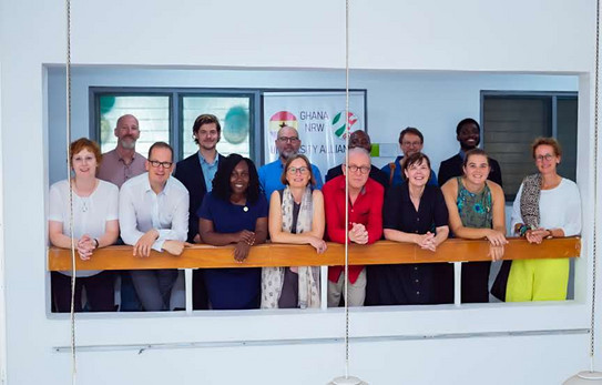Eröffnung des Verbindungsbüros in Accra, Ghana Gruppenfoto mit Damen und Herren aus NRW und Ghana, die vor einem Flurgeländer stehen und lächeln.