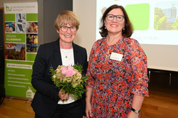 Foto von zwei Frauen. Die linke Frau hält einen Blumenstrauß in der Hand.