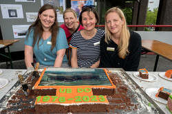 vier Personen sitzen vor einem großen Kuchen