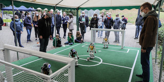 Besucher*innen schauen Robotern beim Fußballspielen zu