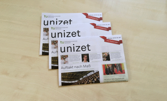 Three issues of unizet lie on top of each other on a table.