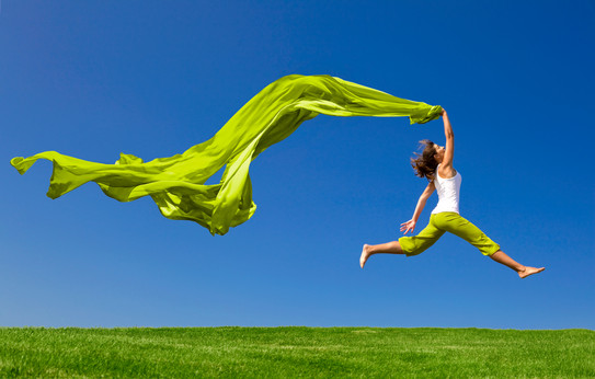 Air Jump A woman jumps across a green meadow against a blue sky. She is waving a long, green scarf.