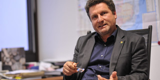 Prof. Christoph Käppler Ein Mann im grauen Anzug sitzt an einem Schreibtisch.