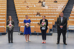 Gruppenfoto mit drei Frauen und drei Männern. Die Personen halten Abstand und die Frauen haben jeweils einen Blumenstrauß in der Hand