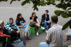 Studierenden sitzen auf grünen Würfeln draußen während eines Study Talks