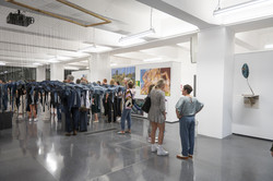 Rundgang Kunst Hängende Plastik Ansicht eines Ausstellungsraums. Links hängt eine große Plastik, im Hintergrund stehen Menschen verteilt im Raum.