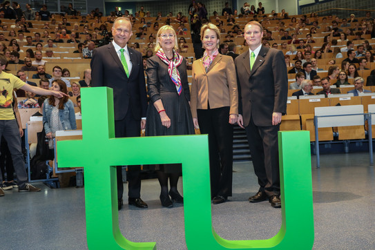 Im Vordergrund steht das TU-Logo, im Hintergrund stehen Andrzej Górak, Ursula Gather, Frances Arnold und Stephan Lütz