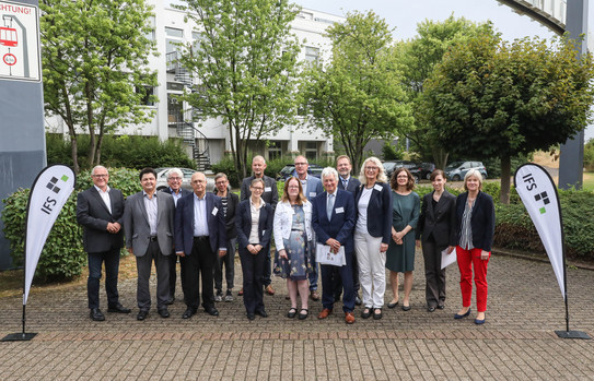Gruppenfoto zwischen "IFS"-Aufstellern vor einem weißen Gebäude