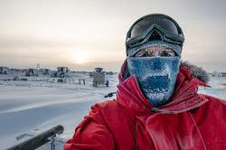 Selfie von einem Mann in roter Jacke, der draußen im Schnee steht und dessen Schal, Wimpern und Augenbrauen von Eis bedeckt sind