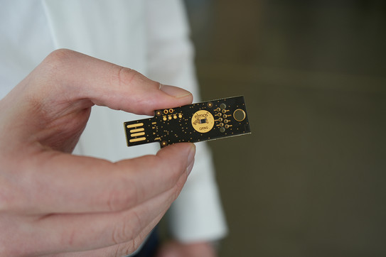 Foto: Eine Hand hält einen kleinen elektronischen Chip zwischen den Fingern.