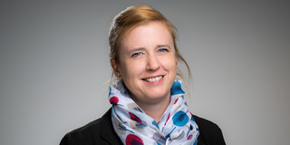 Porträtfoto von Prof. Wiederkehr: Prof. Wiederkehr trägt einen gemusterten Schal und einen schwarzen Blazer. Sie lächelt in die Kamera.
