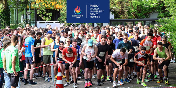 Läufer*innen an der Startlinie des Campuslaufs kurz vor dem Startschuss, oben ist das Logo der FISU-Games ins Bild montiert