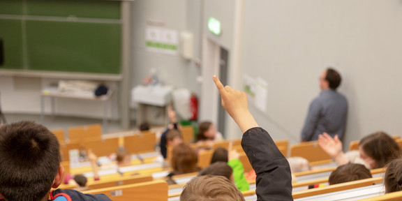 Kinder sitzen in einem Hörsaal einer Universität.