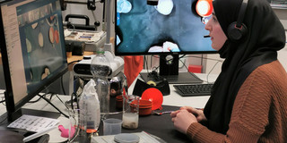 Frau mit Headset sitzt vor zwei Bildschirmen