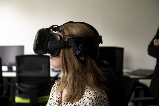 Eine Frau trägt eine Virtual-Reality-Brille auch schaut nach links. 