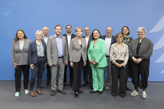 Gruppenfoto: Mitglieder der Altersberichtskommission vor blauer Hintergrundwand.