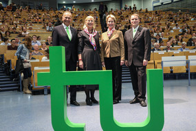 Vier Personen stehen vor Hörsaalpublikum, im Vordergrund TU-Logo