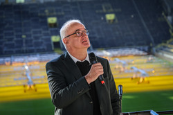 Prof. Manfred Bayer steht auf der Tribüne und spricht in ein Mikrofon.