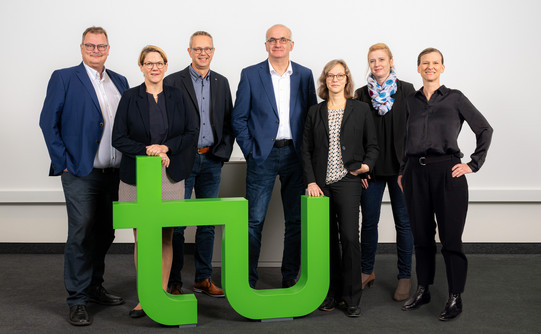 Foto: Das Rektorat der TU Dortmund posiert hinter einem hellgründen TU-Logo. Das Foto zeigt von links nach rechts Prof. Gerhard Schembecker (Prorektor Finanzen), Prof. Wiebke Möhring (Prorektorin Studium), Kanzler Markus Neuhaus, Rektor Prof. Mafred Bayer, Prof. Nele McElvany (Prorektorin Forschung), Prof. Petra Wiederkehr (Prorektorin Diversität) und Prof. Tessa Flatten (Prorektorin Internationales).