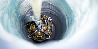 Das Foto zeigt, wie die Glaskugel ins Bohrloch abgelassen wird.