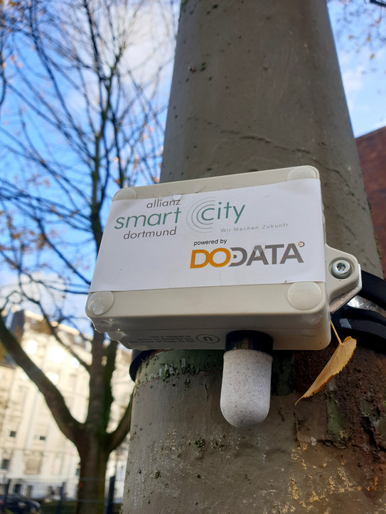 Sensor Das Bild zeigt einen kleinen grauen Kasten mit Sensor an einer Straßenlaterne