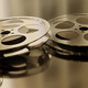 Zwei Filmrollen liegen auf einer spiegelnden Fläche.