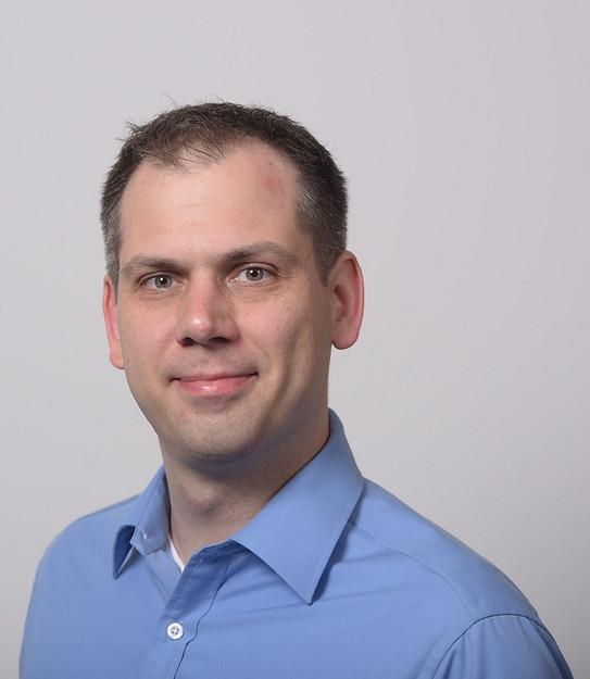 A photo of Prof. Daniel Neider, a man in a light blue shirt.