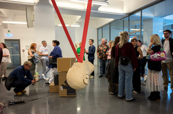 Eine Installation in der Mitte der Galerie. Im Hintergrund stehen weitere Kunstwerke und Besuchende. 